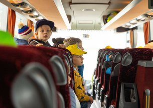 Children look out of the bus window in amazement.
