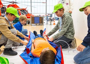 A group of children wrap a boy in a vacuum mattress.