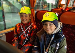 Two boys smile at the camera on the bus.