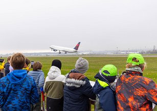 Children watch an aeroplane take off.
