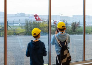 Two children watch a Rega jet leaving the hangar.