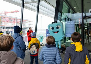 The mascot Rolli Rollkoffer greets the children at the airport.