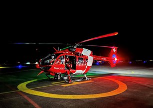 Un hélicoptère de sauvetage, la nuit, posé sur un héliport 