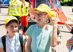 Kinder stehen vor dem Rettungshelikopter und stellen Fragen.