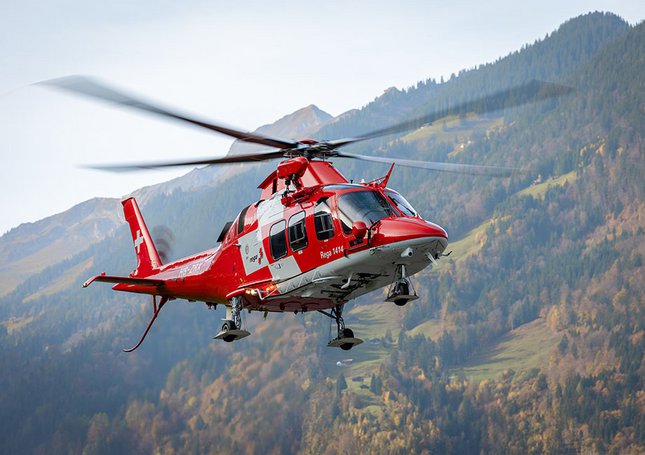 Ein Rettungshelikopter fliegt über eine bewaldete Hügellandschaft