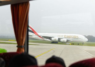 An Emirates aeroplane can be seen through the bus window.
