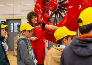 The engineer explains something about the helicopter to the children.