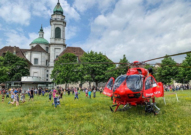 Des enfants courent vers un hélicoptère de la Rega pour l’observer de plus près