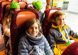 Two boys smile at the camera on the bus.