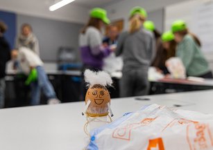 A decorated egg stands on the craft table.