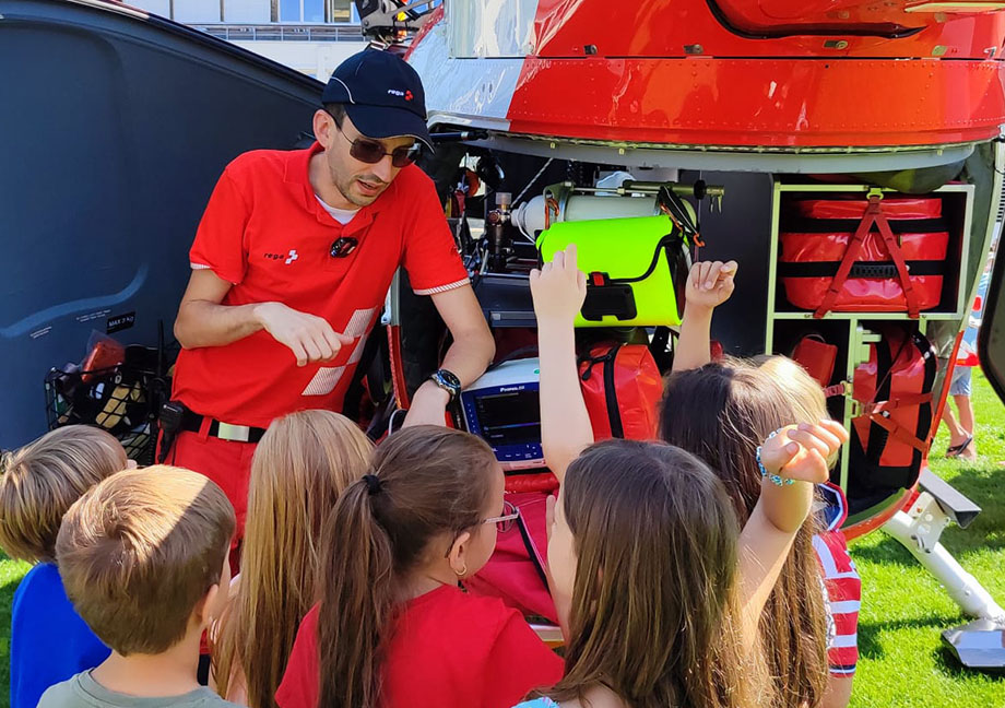 I bambini osservano da vicino l'elicottero di soccorso e pongono domande al medico d'urgenza della Rega