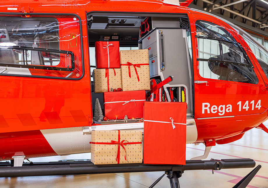 Rega helicopter with the side door open and several wrapped gifts placed inside